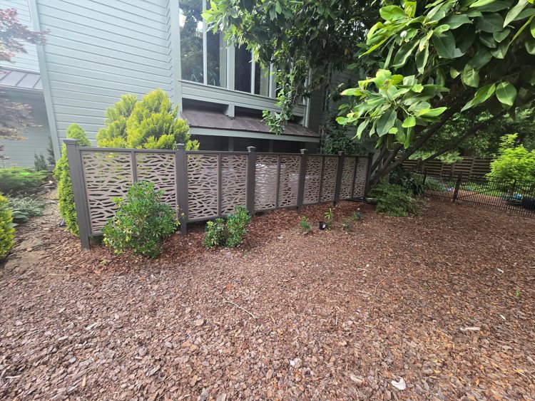 Fence with decorative branch-pattern panels between capped posts