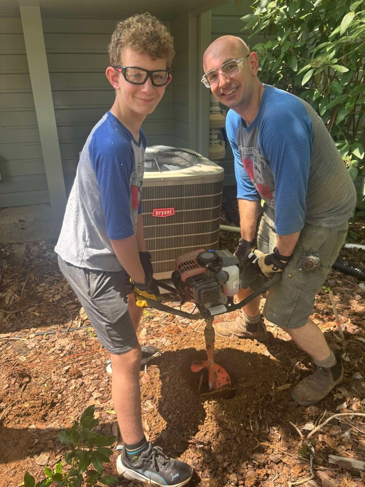 Pete and his son working together with a post-hole auger
